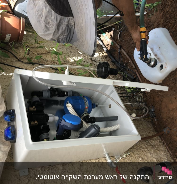 מערכת השקיה עם צינורות ומיכל מים בגינה